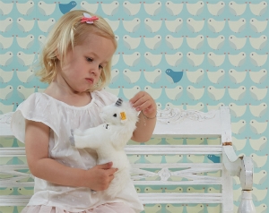 kinderbehang met vogelpatroon in lichtblauw met meisje ervoor