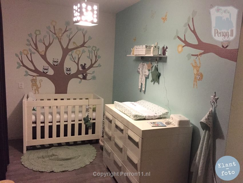 Babykamer met zachte pasteltinten en muurstickerboom